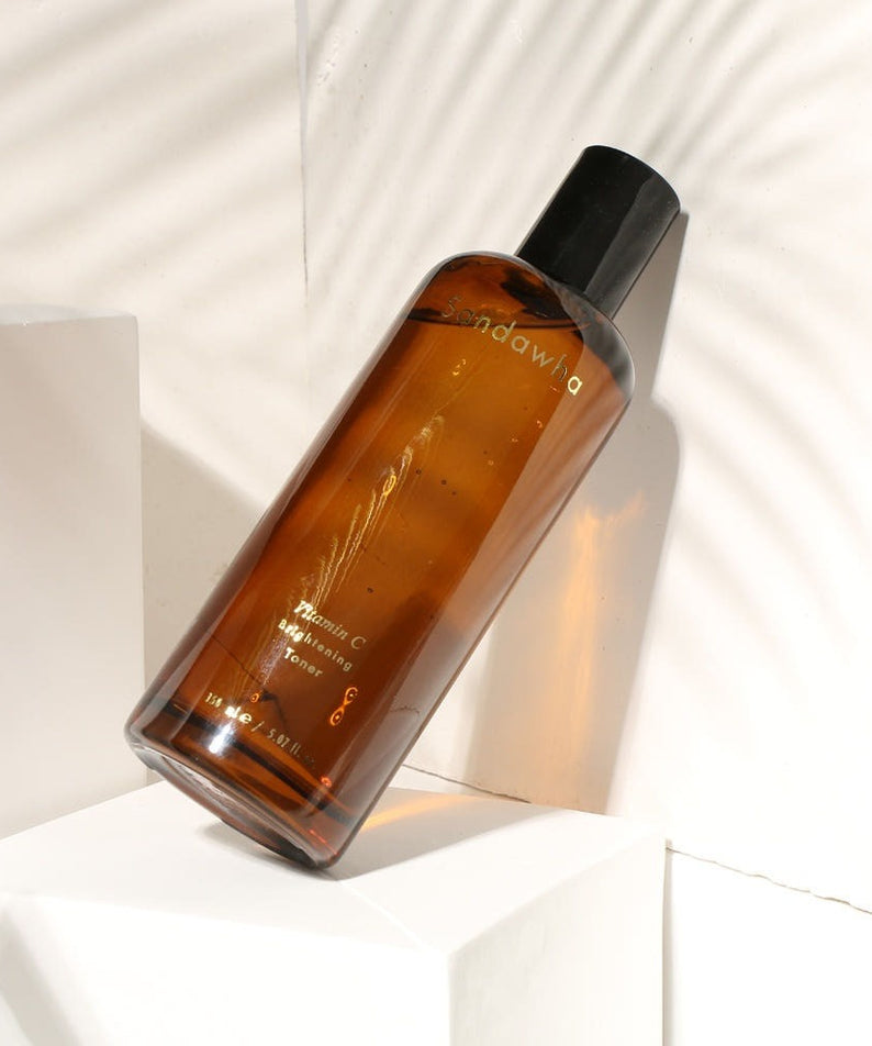 SANDAWHA Vitamin C Whitening Toner 150ml, flacon ambré sur fond blanc, marque en contexte visuel lifestyle