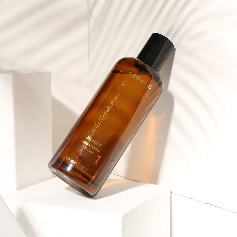 SANDAWHA Vitamin C Whitening Toner 150ml, flacon ambré sur fond blanc, marque en contexte visuel lifestyle