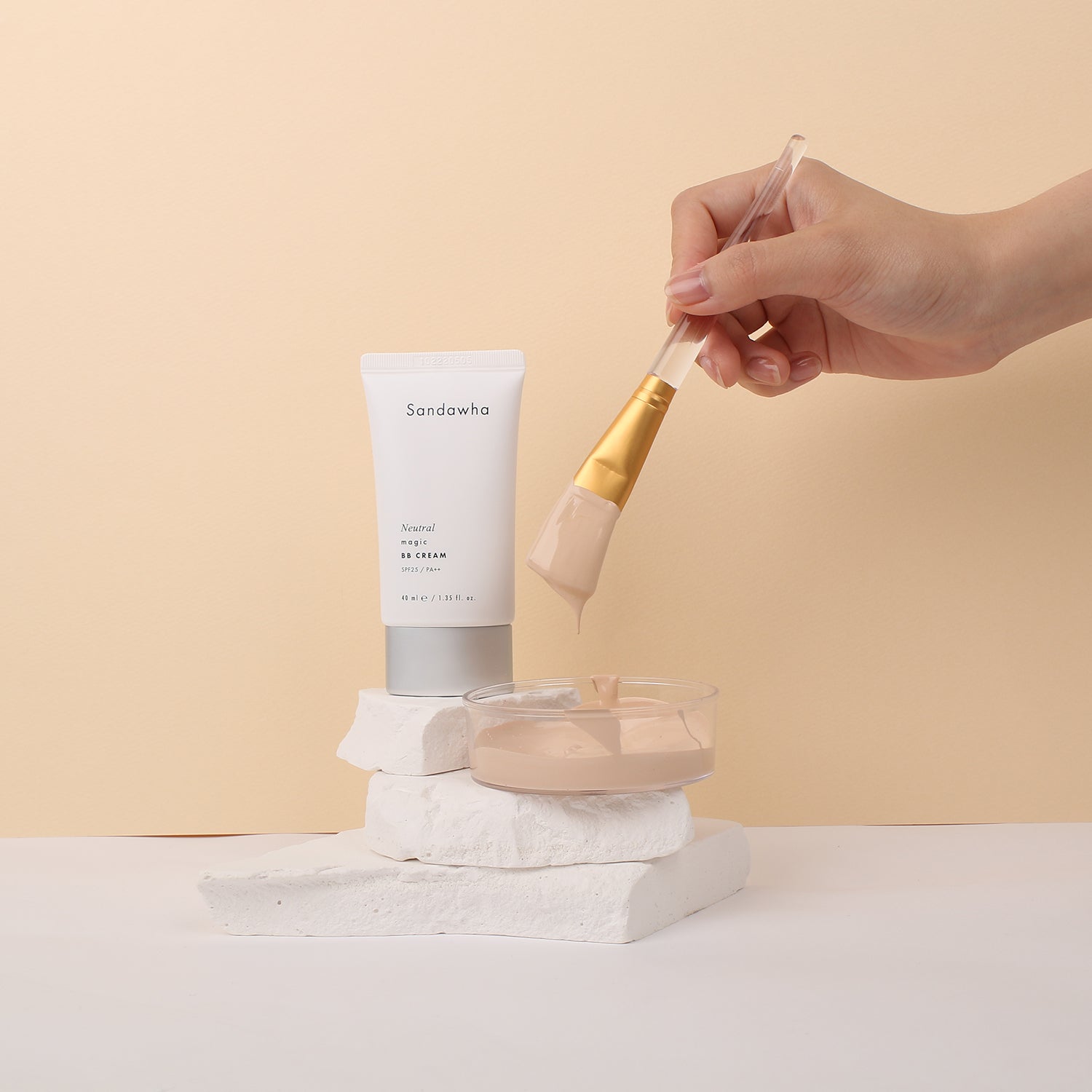 Décris l'image en français : SANDAWHA Neutral Magic BB Cream SPF25 PA++ 40ml, tube sur fond beige, main applique une crème.