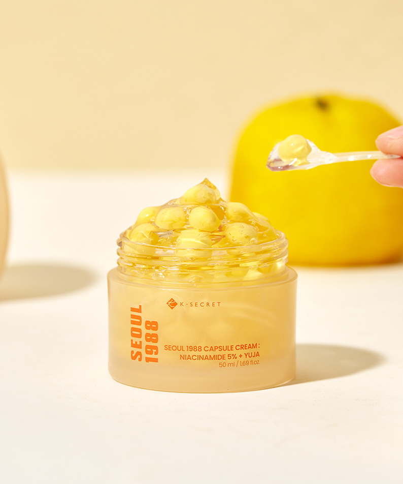 Décrivez l’image : pot de crème SEOUL 1988  Niacin Yuja Capsule Cream 50ml, marque sur packaging, crème dorée à la main