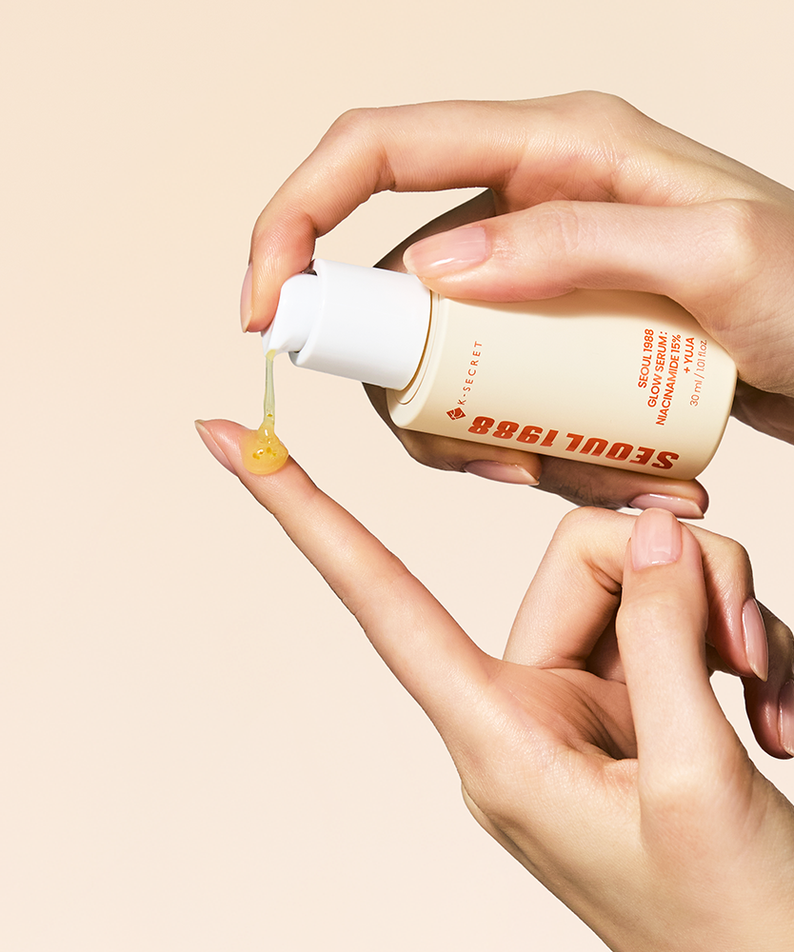 Main tenant SEOUL 1988  Niacin Yuja Serum 30ml, gouttes jaunes, fond beige, contexte skincare beauté.