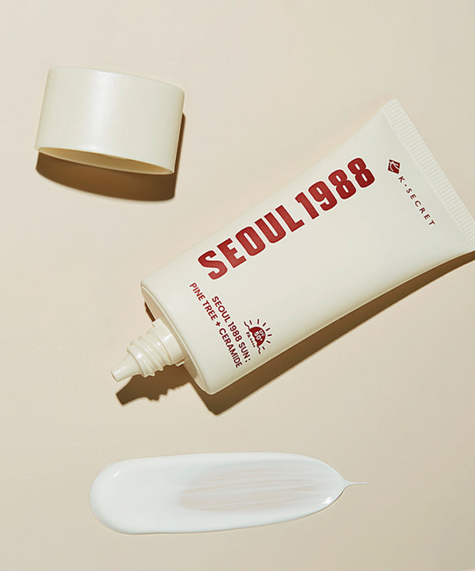 Crème solaire SEOUL 1988 Pine Sunscreen avec bouchon ouvert et crème étalée en gros plan sur fond beige.