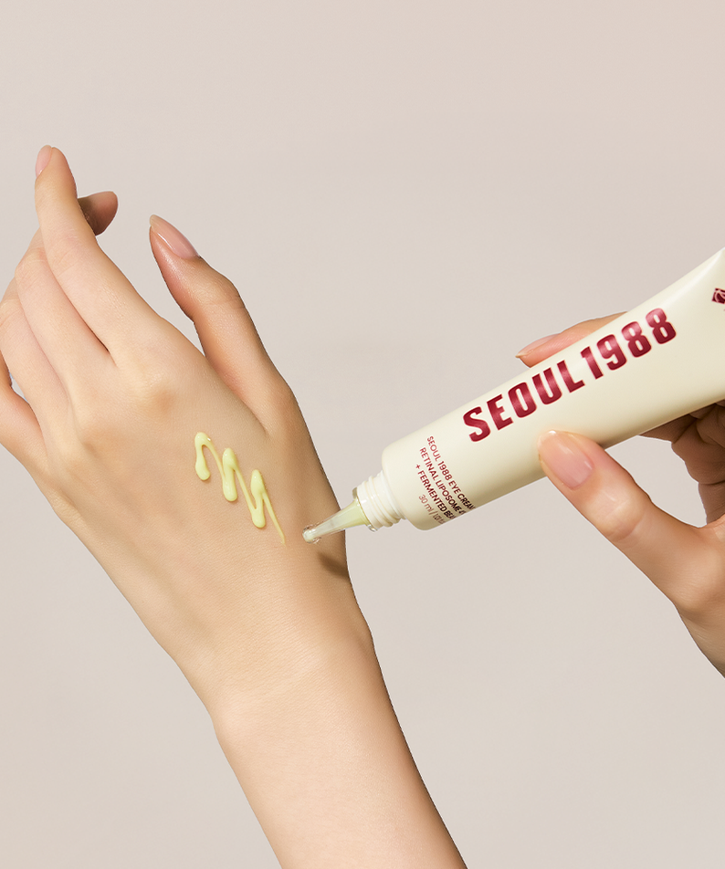 SEOUL 1988 Retinal Fermented Soybean Eye Cream 30ml, tube crème autour des yeux, mains en gros plan sur fond beige.