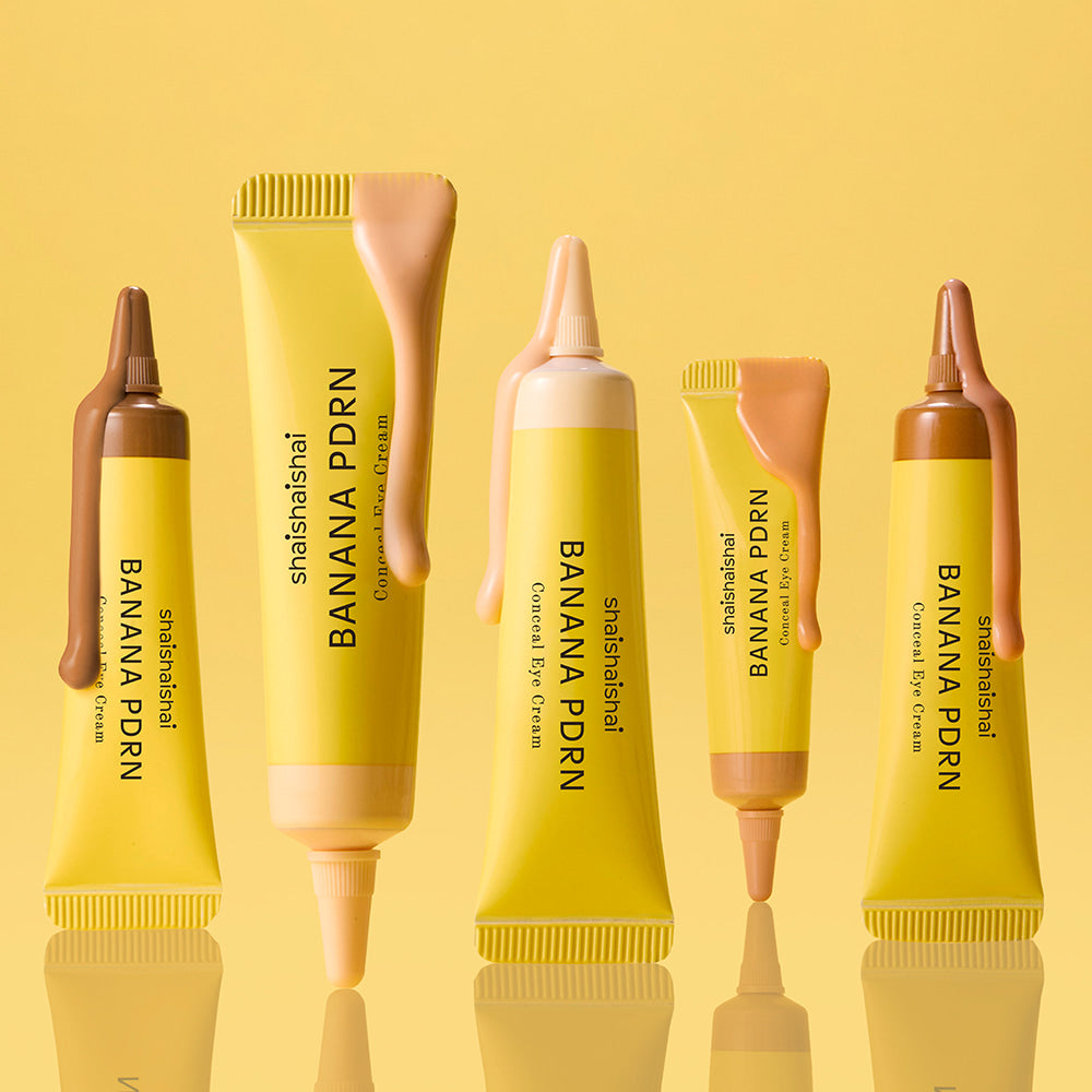SHAISHAISHAI Banana PDRN Conceal Eye Cream 15ml, tubes jaunes sur fond jaune en contexte maquillage beauté.