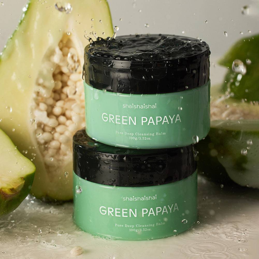 Décris l'image en français : SHAISHAISHAI Green Papaya Pore Deep Cleansing Balm 85ml, pot vert sur fond de papaye verte et eau.