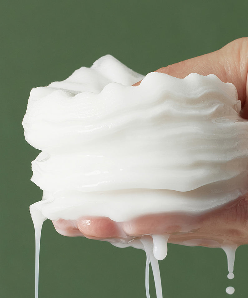 Main tenant un SHAISHAISHAI Repair Milky Skin Peel Pad 60 Pads 120ml, texture crémeuse sur fond vert.