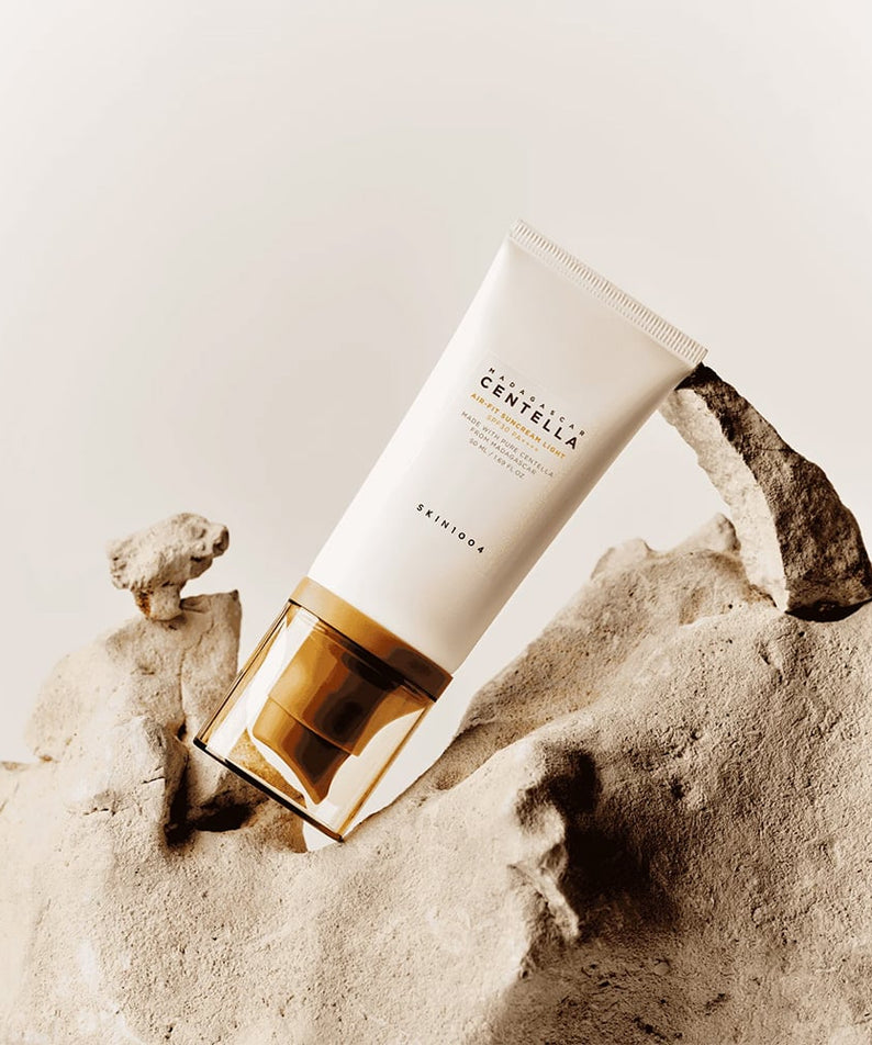SKIN1004 Madagascar Centella Air-fit Sunscreen Light 50ml, SKIN1004, tube posé sur sol minéral beige.