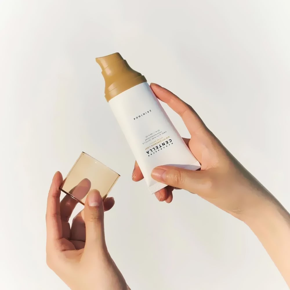 SKIN1004 Madagascar Centella Air-fit Sunscreen Light 50ml, main tenant un flacon crème solaire sur fond clair, vue produit.
