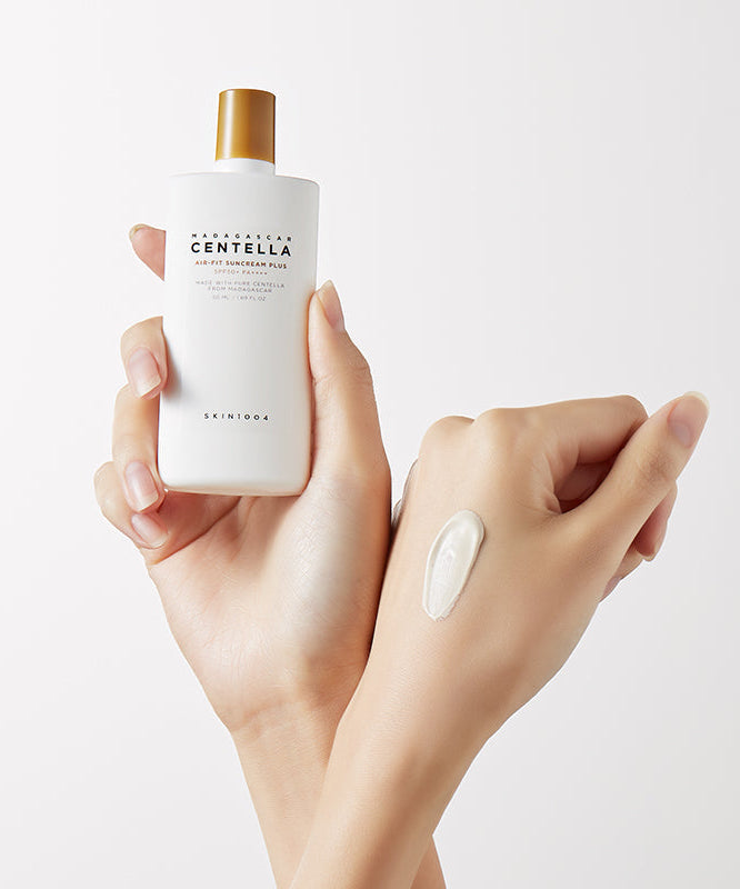 SKIN1004 Madagascar Centella Air-fit Sunscreen Plus 50ml, flacon crème solaire sur mains, marque SKIN1004, fond clair.