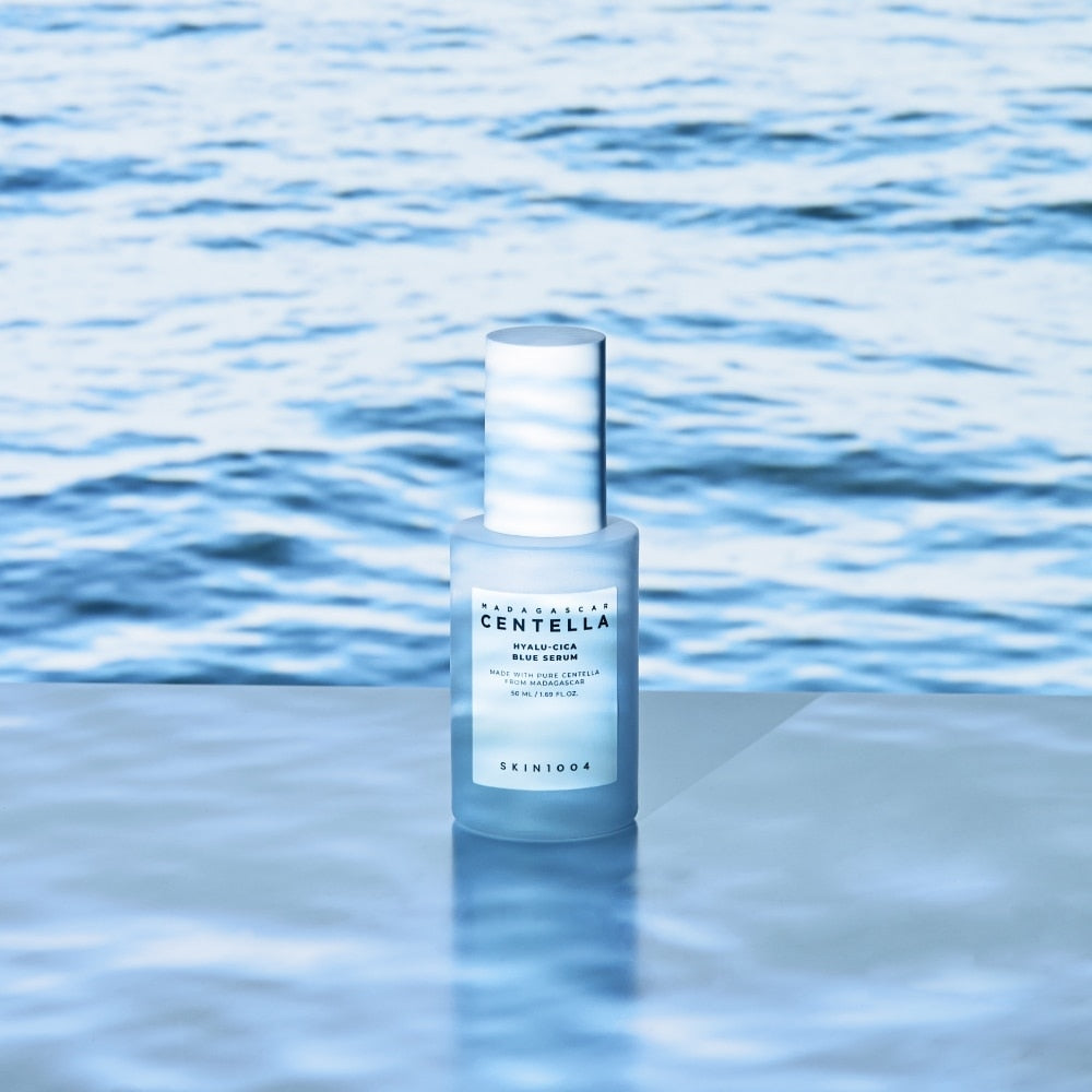 SKIN1004 Madagascar Centella Hyalu-Cica Blue Serum 50ml, flacon bleu sur fond d’eau, marque SKIN1004, contexte spa/rafraîchissant.