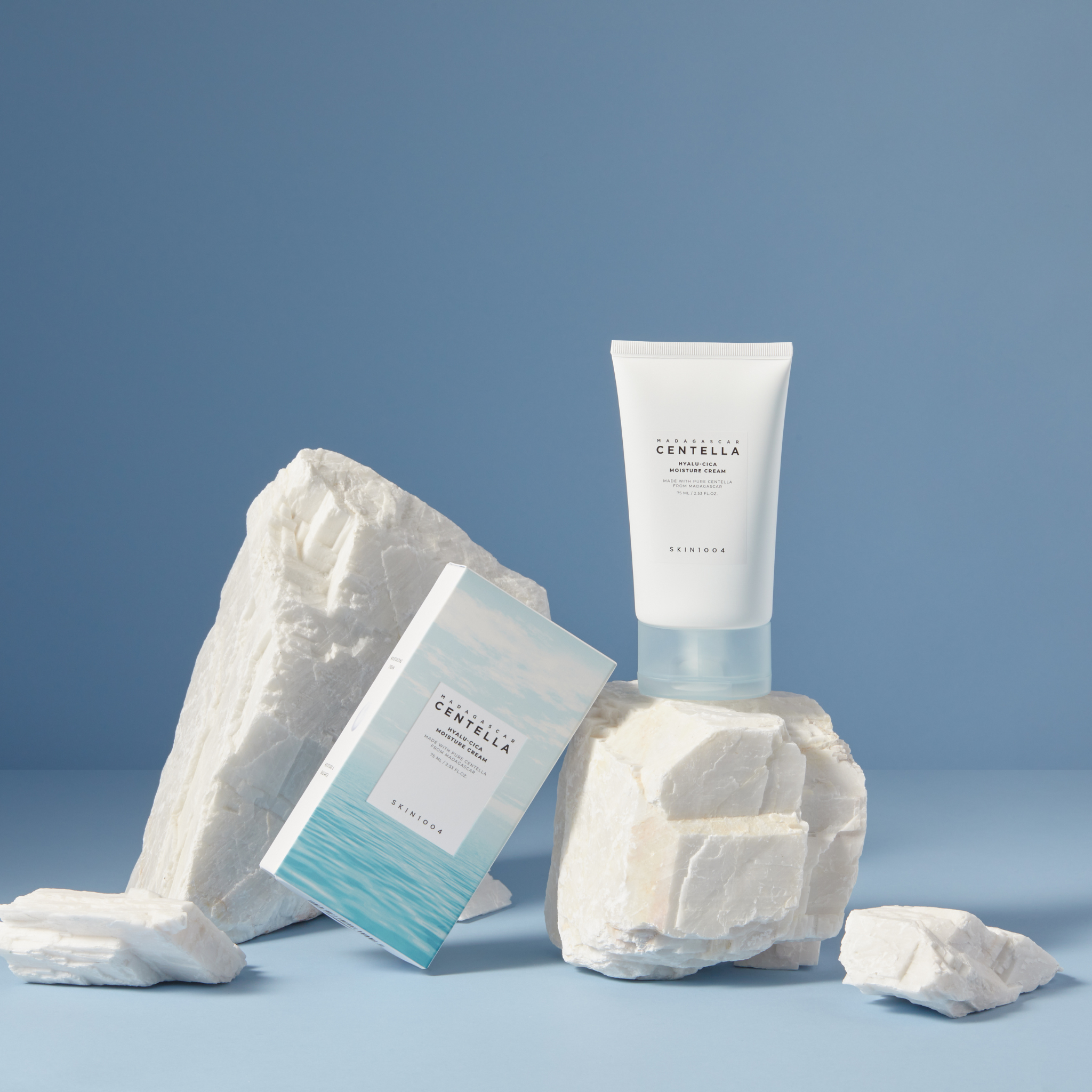 Décris l'image en français: SKIN1004 Madagascar Centella Hyalu-Cica Moisture Cream 75ml, tube blanc SKIN1004 sur fond bleu