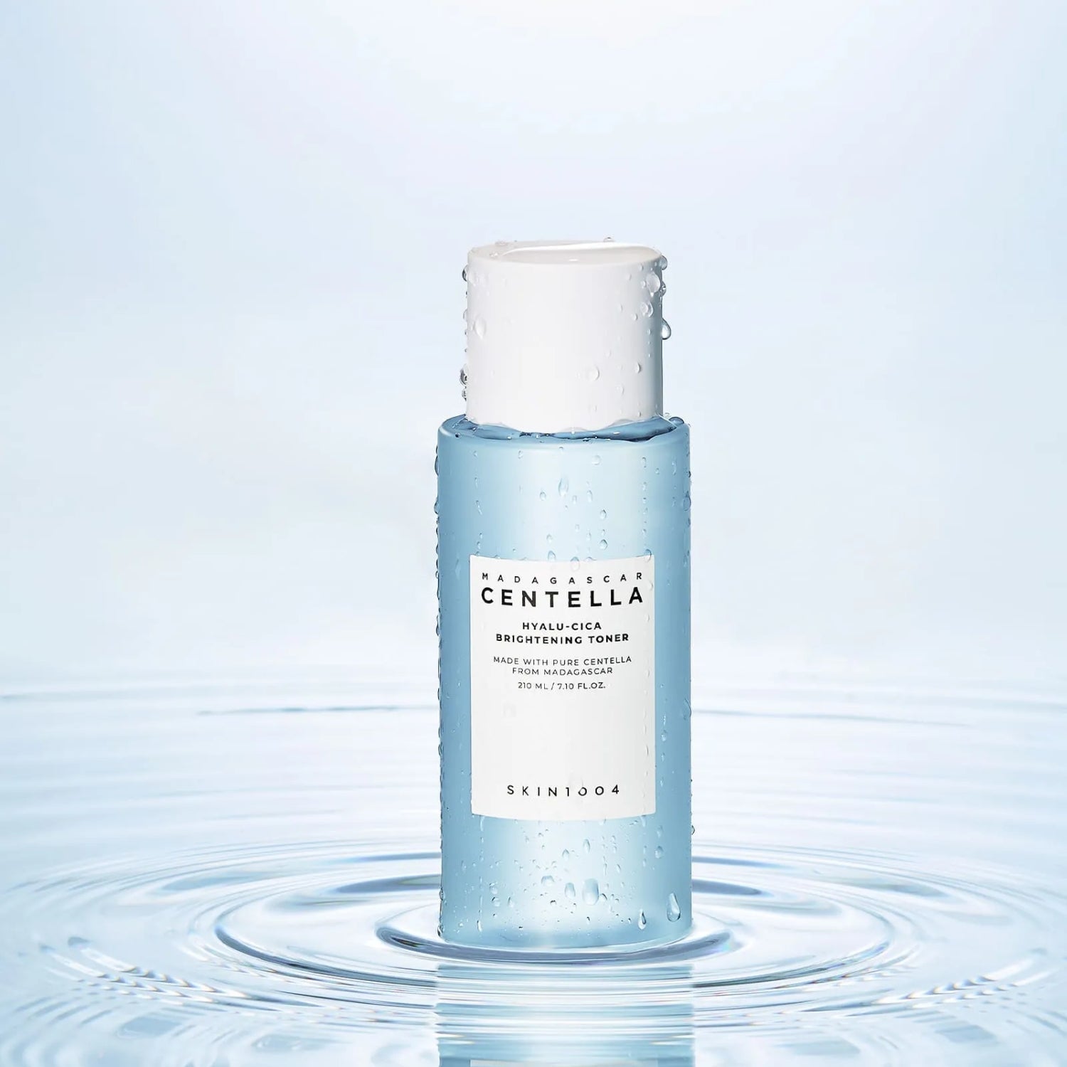 SKIN1004 Madagascar Centella Hyalu-Cica Radiance Toner 210ml, marque SKIN1004, flacon sur fond bleu, gouttes d’eau.