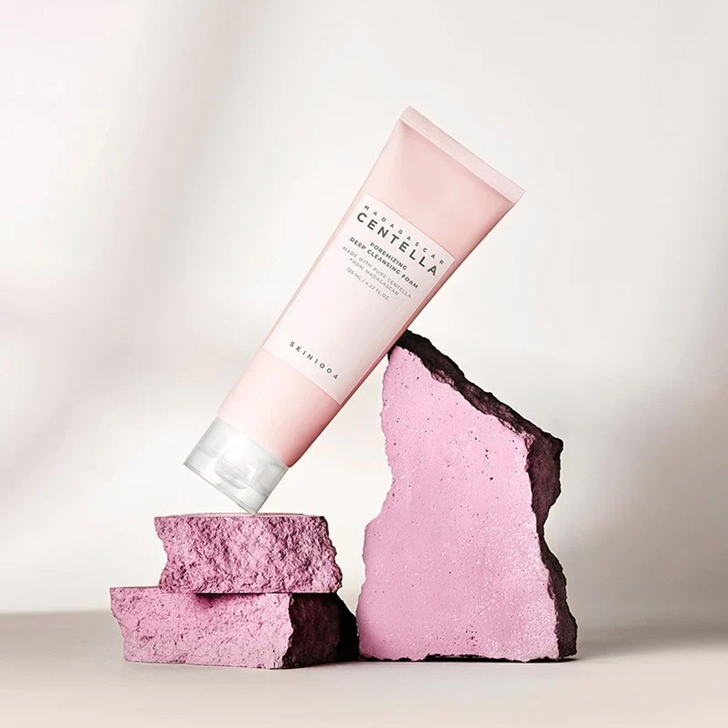 SKIN1004 Madagascar Centella Poremizing Deep Cleansing Foam 125ml de la marque SKIN1004, tube rose sur fond clair, mousse/pierre.