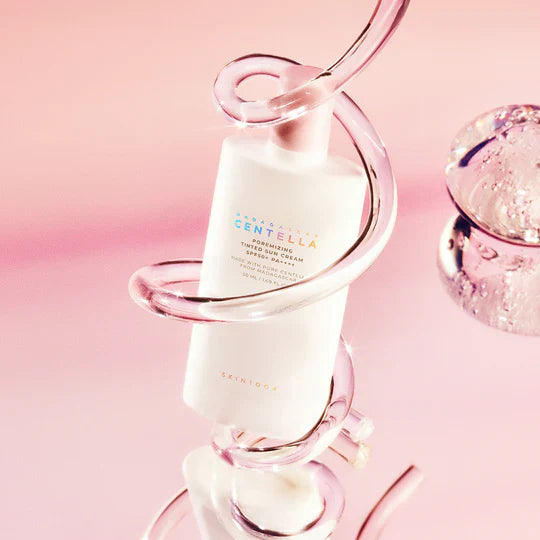 SKIN1004 Madagascar Centella Poremizing Velvet Finish Sunscreen 50ml : flacon en verre, fond rose, gouttes et bulles, produit skincare.