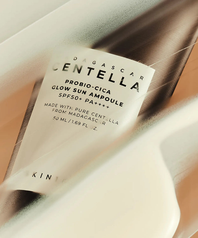 Décris l'image en français : SKIN1004 Madagascar Centella Probio-cica Glow Sun Ampoule 50ml, flacon sur fond beige, marque affichée