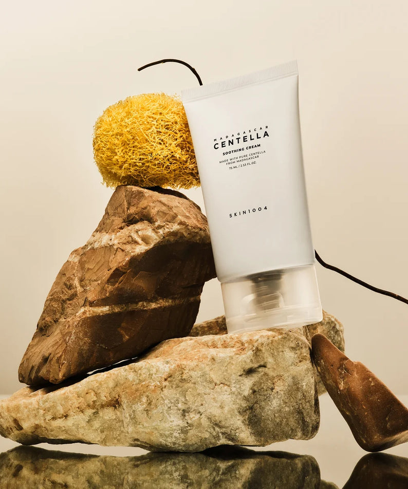 SKIN1004 Madagascar Centella Soothing Cream 75ml, tube SKIN1004 sur galets et éponge, contexte beauté spa.