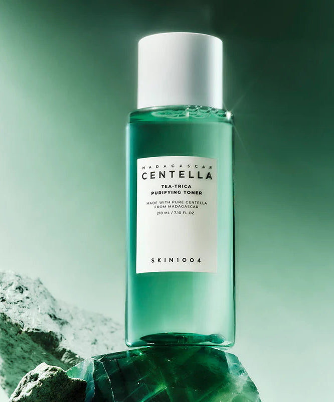 SKIN1004 Madagascar Centella Tea-trica Purifying Toner 210ml, produit SKIN1004 sur fond vert et pierres, contexte skincare.