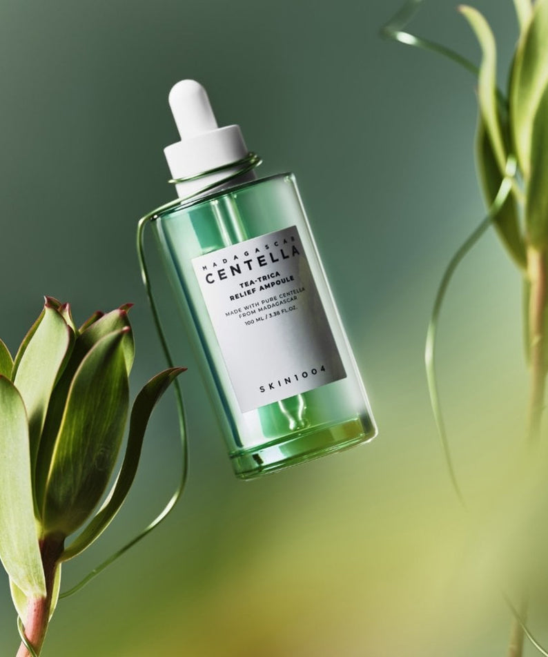 SKIN1004 Madagascar Centella Tea-trica Relief Ampoule 100ml de SKIN1004, flacon vert sur fond vert avec plantes.