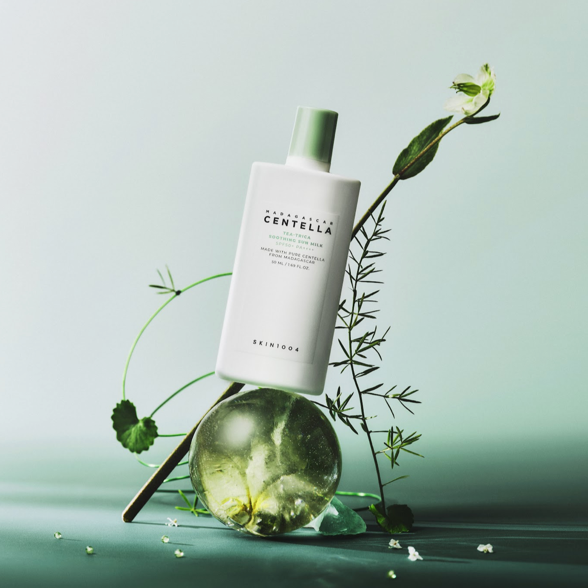 Décris l'image en français: SKIN1004 Madagascar Centella Tea-trica Soothing Sun Milk 50ml de SKIN1004, flacon sur fond vert.