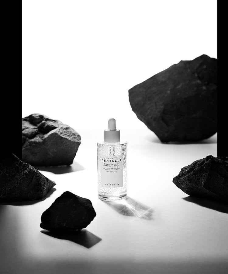 SKIN1004 Madagascar Centella Tone Brightening Capsule Ampoule 100ml de la marque SKIN1004, flacon au milieu de pierres noires sur fond blanc.