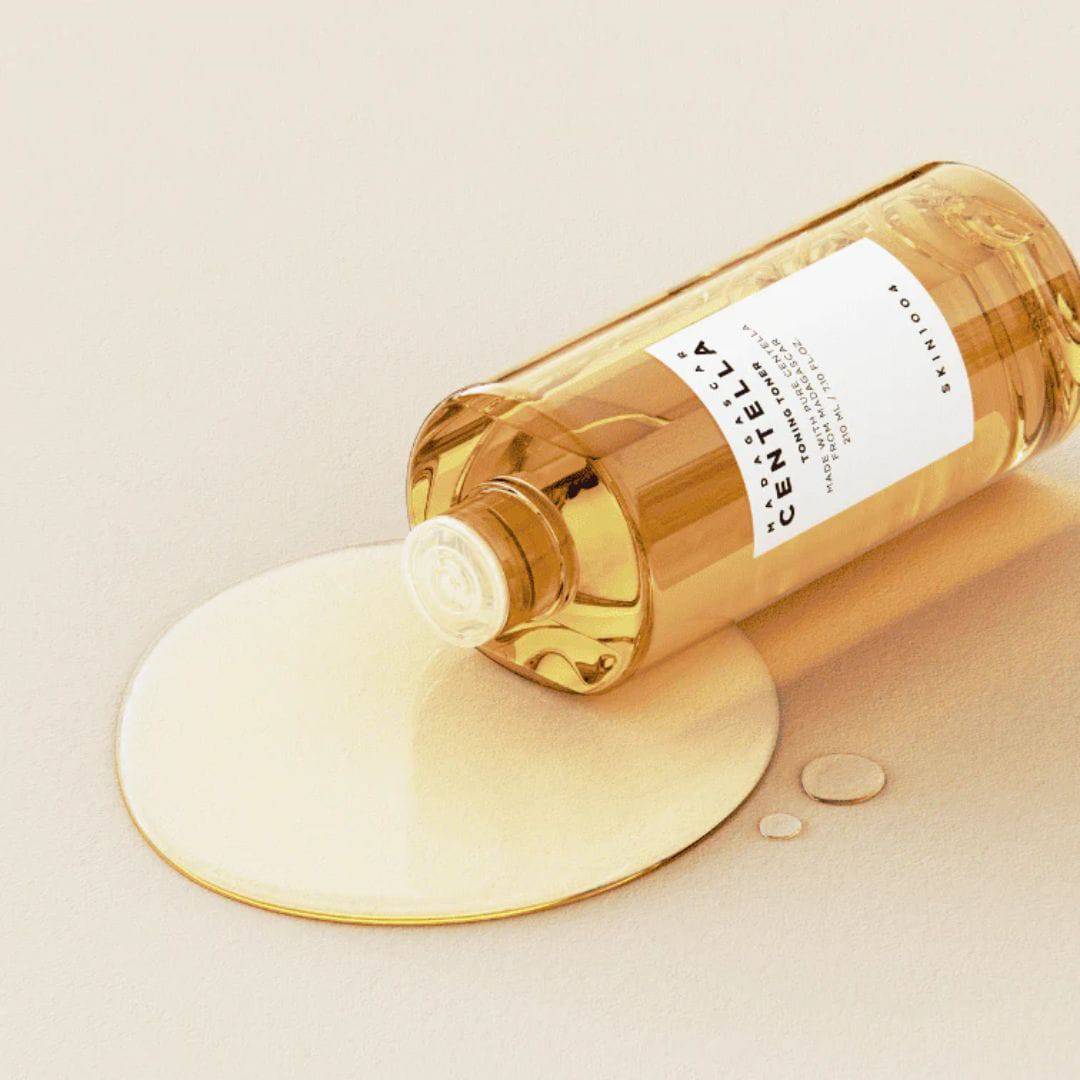 SKIN1004 Madagascar Centella Toning Toner 400ml de la marque SKIN1004, flacon ambre versant sur crème, fond clair