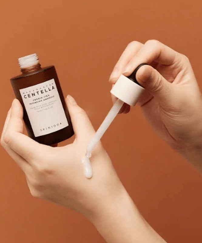 Application du SKIN1004 Madagascar Centella Probio-cica Intensive Ampoule 50ml sur la main avec un compte-gouttes. Produit cosmétique hydratant.