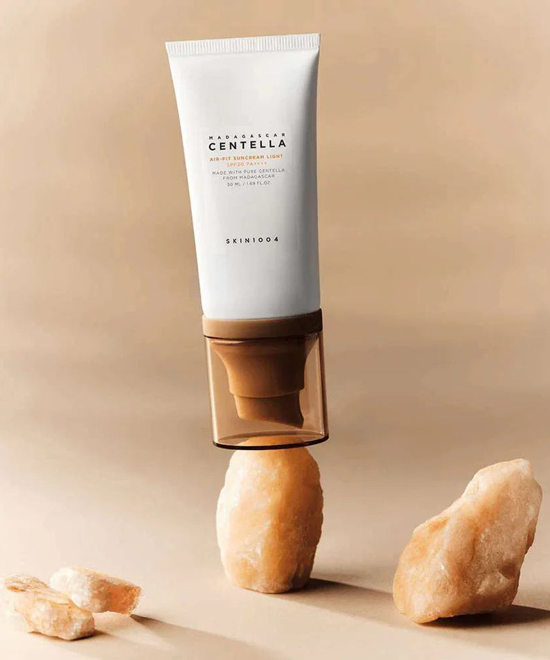 SKIN1004 Madagascar Centella Air-fit Sunscreen Light 50ml sur fond de pierres, protection solaire légère et hydratante.
