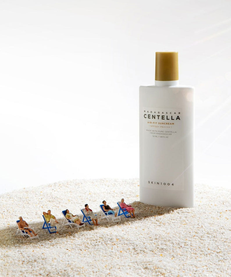 SKIN1004 Madagascar Centella Air-fit Sunscreen Plus 50ml sur sable avec miniatures bronzantes. Parfait pour protéger votre peau.