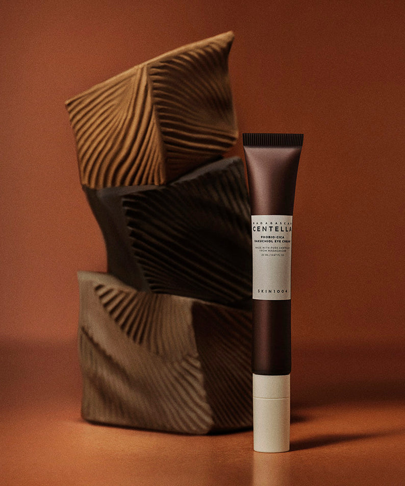 Crème pour les yeux SKIN1004 Madagascar Centella Probio-cica Bakuchiol 20ml sur fond artistique brun et texturé.