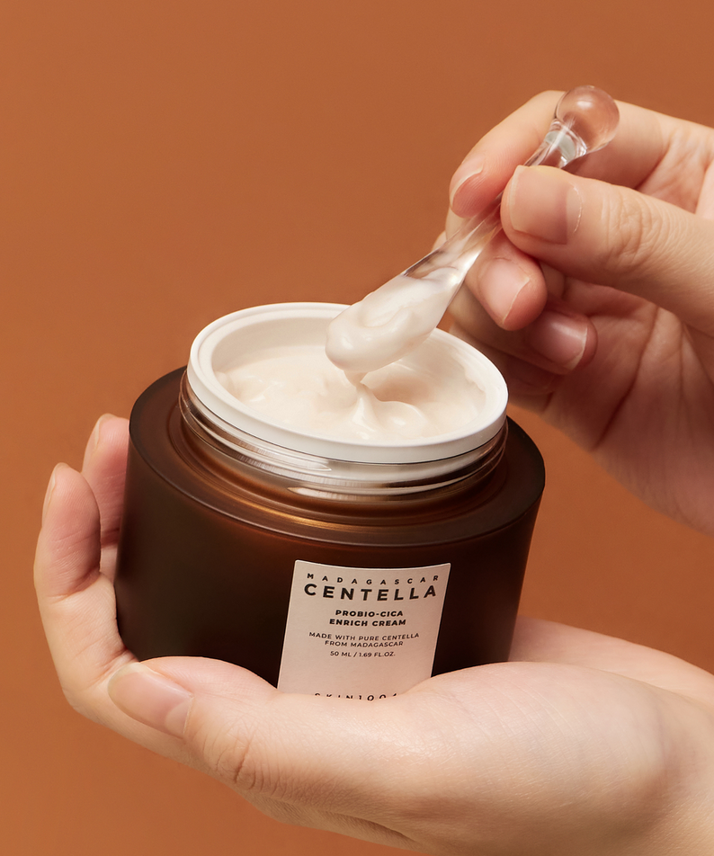 Appliquer la crème SKIN1004 Madagascar Centella Probio-cica Enrich Cream 50ml avec une spatule dans un pot en mains