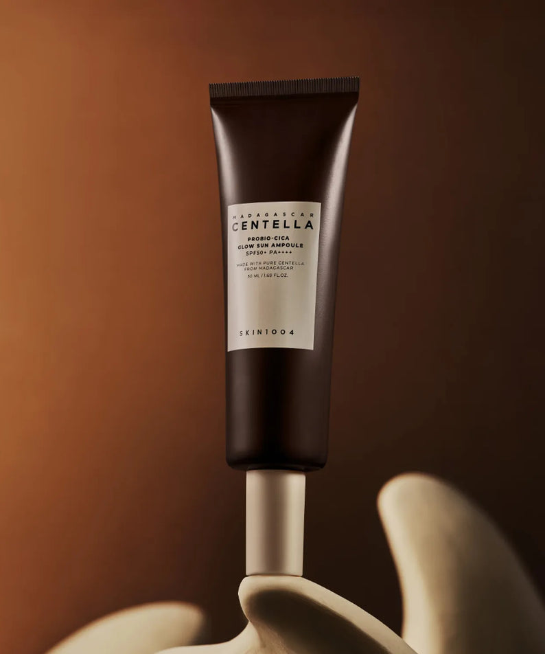 Tube de SKIN1004 Madagascar Centella Probio-cica Glow Sun Ampoule 50ml sur fond marron élégant.