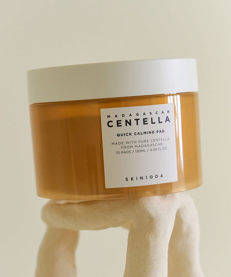 Boîte de SKIN1004 Madagascar Centella Quick Calming Pads 70 sheets posée sur une main en céramique.