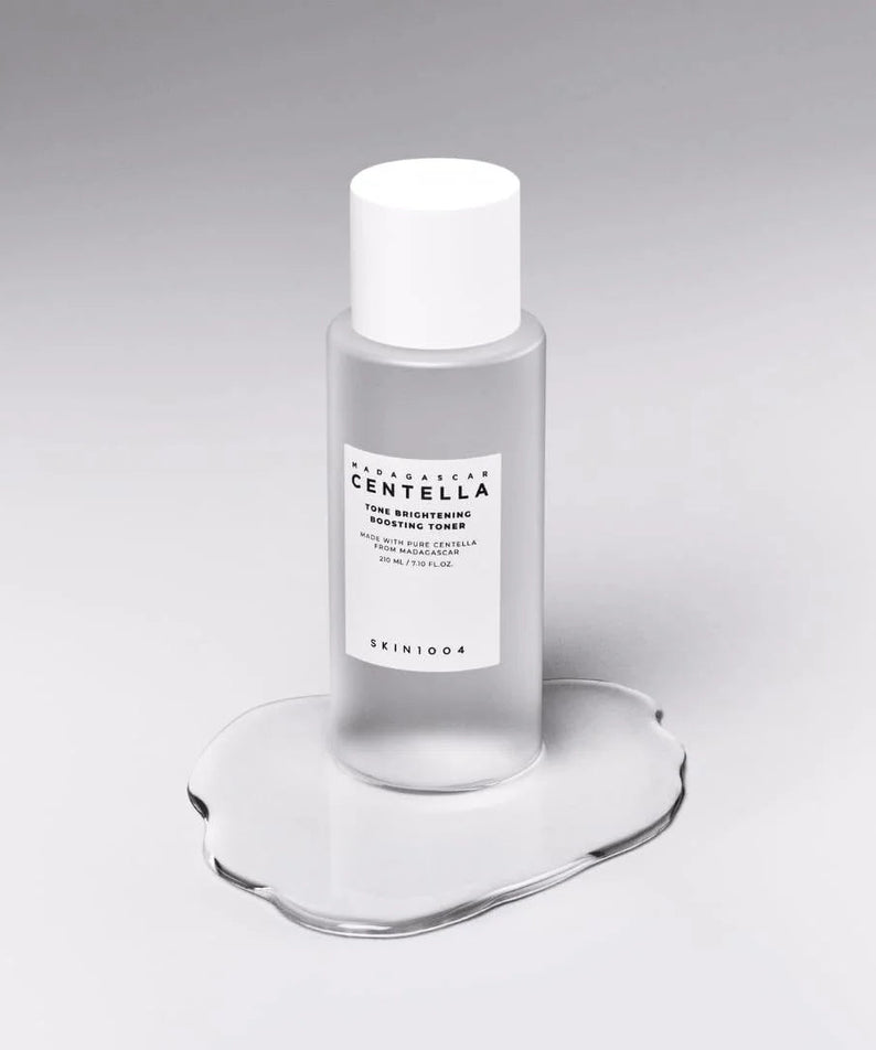 SKIN1004 Madagascar Centella Tone Brightening Boosting Toner 210ml sur une surface en verre, vu de côté.