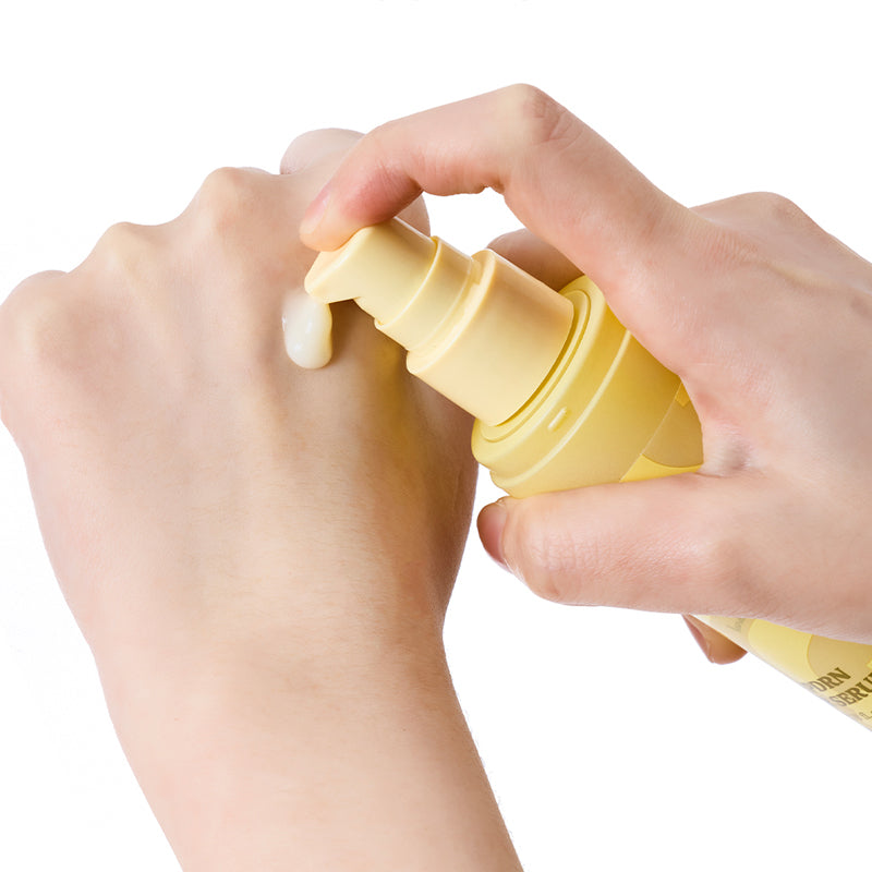 SKINFOOD Banana PDRN Booster Serum 80ml de la marque SKINFOOD, mains tenant le flacon jaune sur fond blanc.