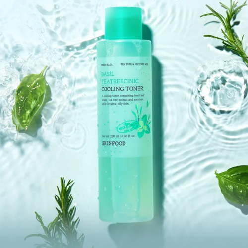 Décris l'image en français : SKINFOOD Basil Tea Tree Cynic Cooling Toner 200ml, flacon vert près de basilic et eau fraîche.