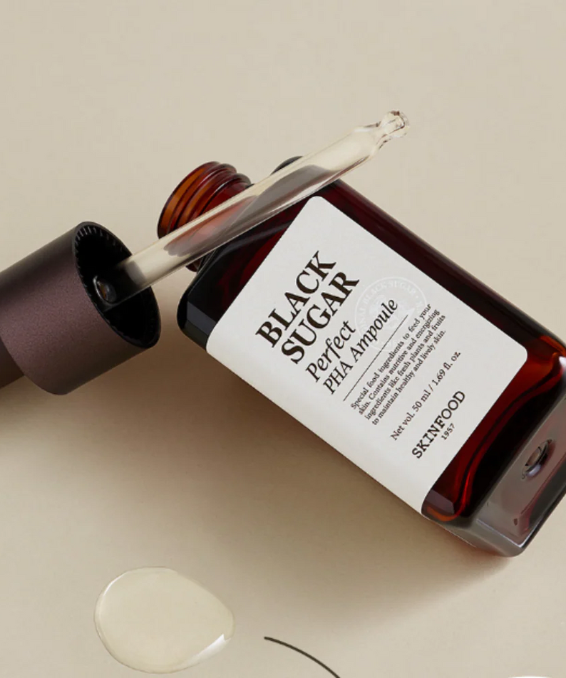 SKINFOOD Black Sugar Perfect PHA Ampoule 50ml, flacon et gouttes d’ampoule sur fond beige, look cosmétique marque SKINFOOD.