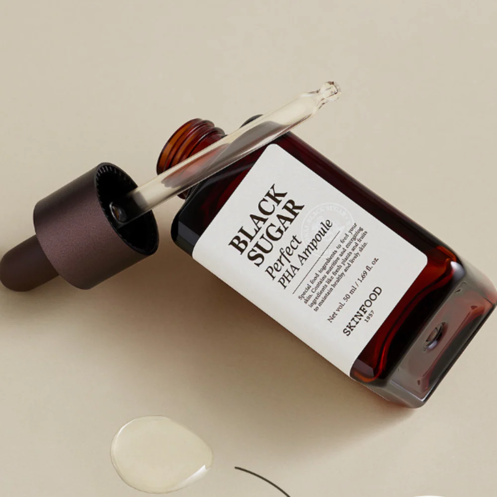 SKINFOOD Black Sugar Perfect PHA Ampoule 50ml, flacon et gouttes d’ampoule sur fond beige, look cosmétique marque SKINFOOD.