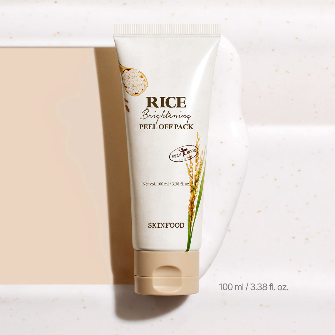 SKINFOOD [NEW] Rice Brightening Peel-Off Pack 100ml, tube crème blanc sur fond beige, packaging SKINFOOD.