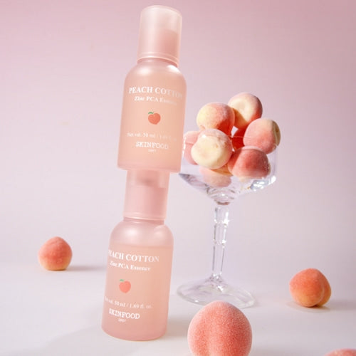SKINFOOD Peachy Zinc PCA Essence 50ml de SKINFOOD sur fond rose, flacon et boules de coton, contexte beauté.