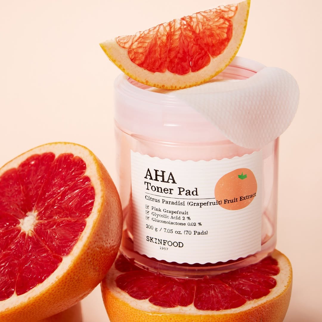 SKINFOOD Pink Grapefruit AHA Toner Pad 70 sheets, flacon et pads à côté de pamplemousse, contexte visuel beauté
