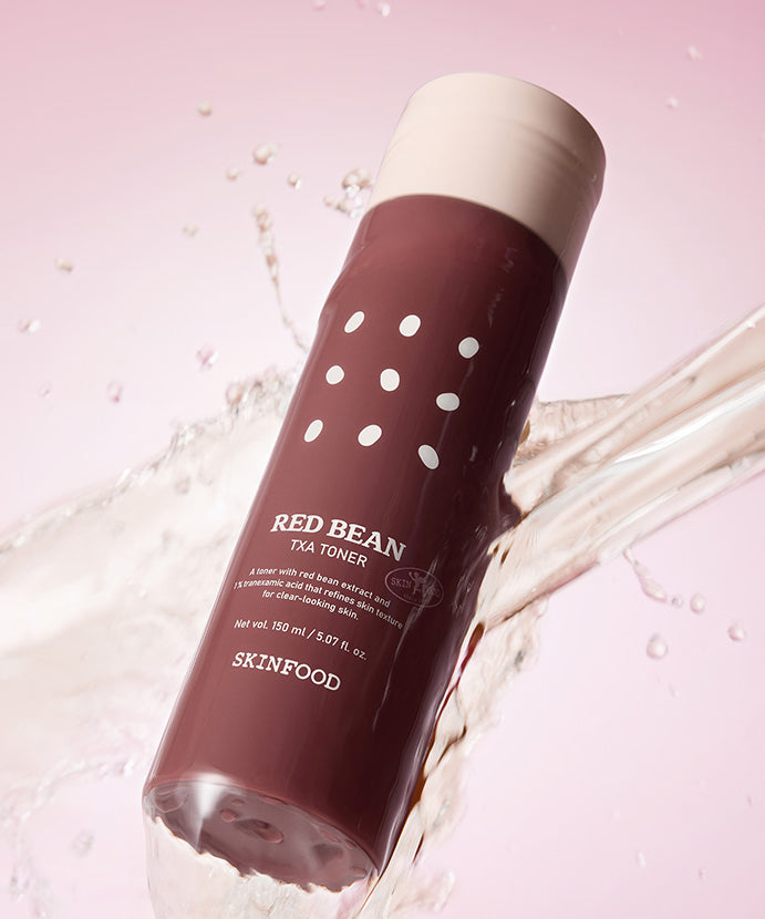SKINFOOD Red Bean Tranexamic Acid Toner 150ml, bouteille sur fond rose avec éclaboussures d’eau, visuel produit.