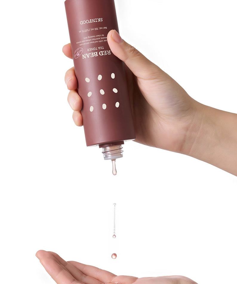 SKINFOOD Red Bean Tranexamic Acid Toner 150ml, main tenant le flacon crème brune sur fond blanc