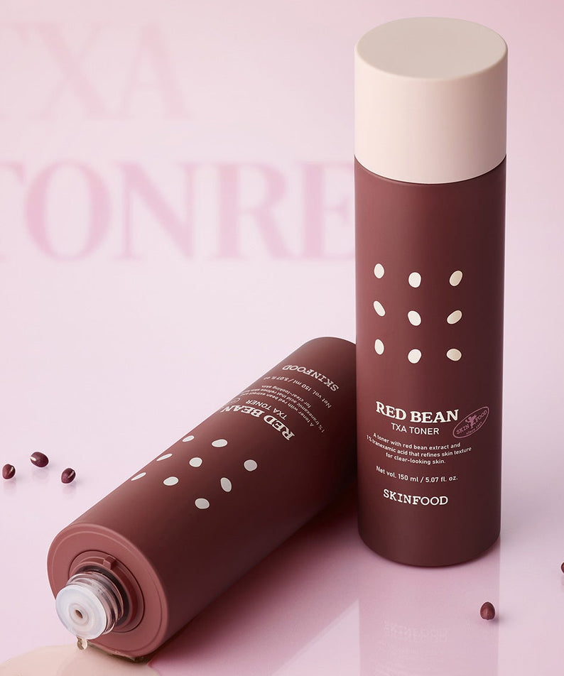 SKINFOOD Red Bean Tranexamic Acid Toner 150ml de la marque SKINFOOD, en flacon sur fond rose, éclats de haricots