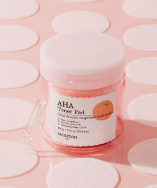 SKINFOOD Pink Grapefruit AHA Toner Pad 70 sheets pour une peau radieuse sur fond rose élégante, produit de beauté coréen.