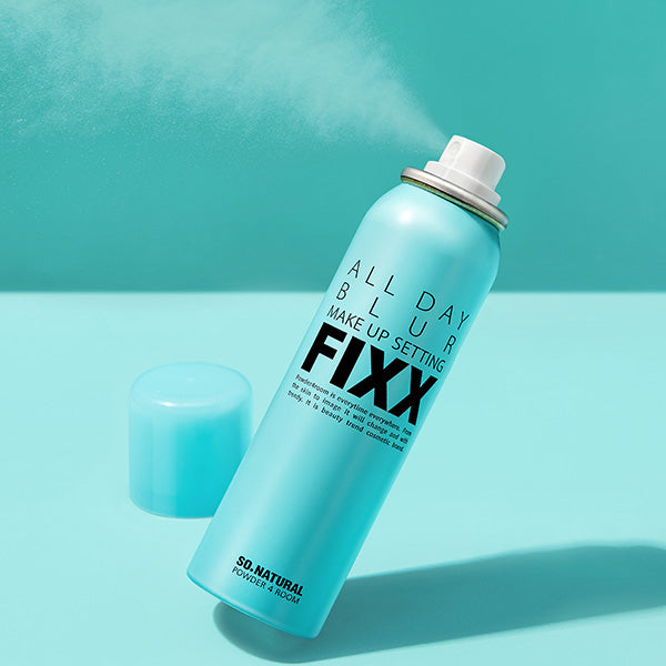 SO NATURAL All Day Blur Makeup Setting Fixer 120ml, flacon bleu sur fond turquoise, ambiance maquillage en studio.