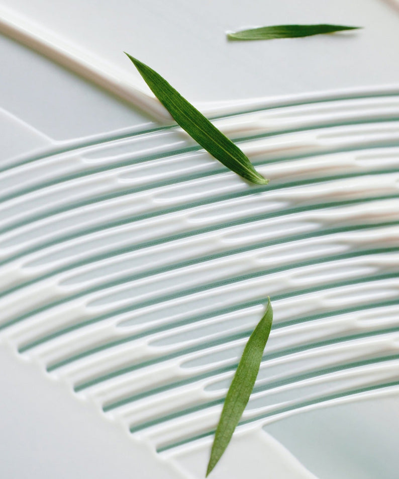 Texture de la crème solaire SOME BY MI Truecica Aqua Calming Sun Cream 50ml, avec des feuilles, détail.