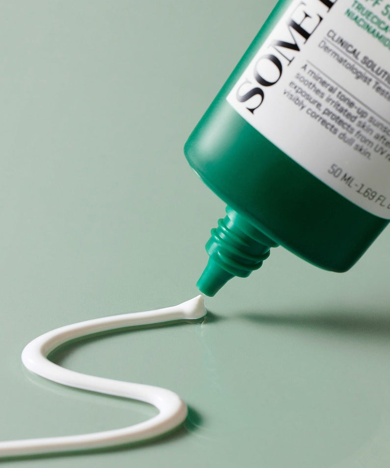 Crème solaire SOME BY MI Truecica Weaponless Calming Tone Up Sun Cream 50ml s'écoulant du tube, montrant la texture apaisante et tonifiante.