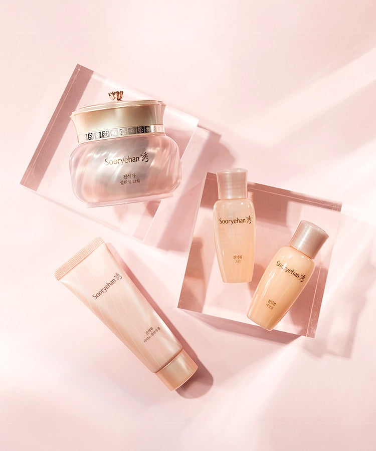 Collection comprenant SOORYEHAN Ultimate Cream 50ml avec différents soins de beauté sur fond rose élégant.
