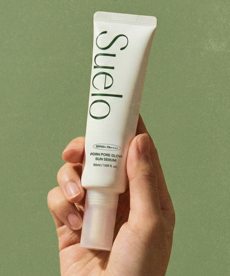 SUELO PDRN Pore Glow Sun Serum 50ml en tube tenu sur fond vert, marque SUELO, contexte photo produit