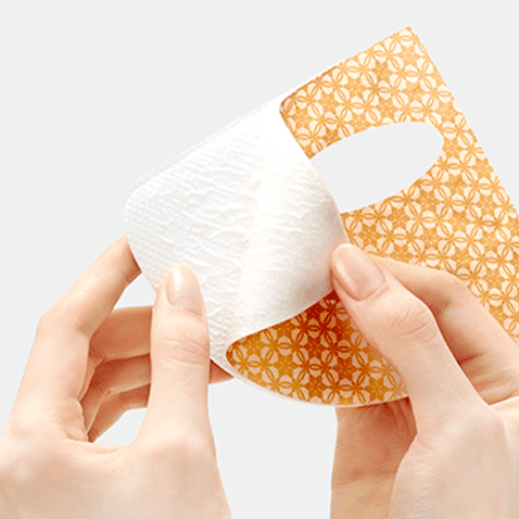 SULWHASOO Concentrated Ginseng Renewing Creamy Mask EX 5 sheets, mains tenant un masque tissu blanc sur fond clair.